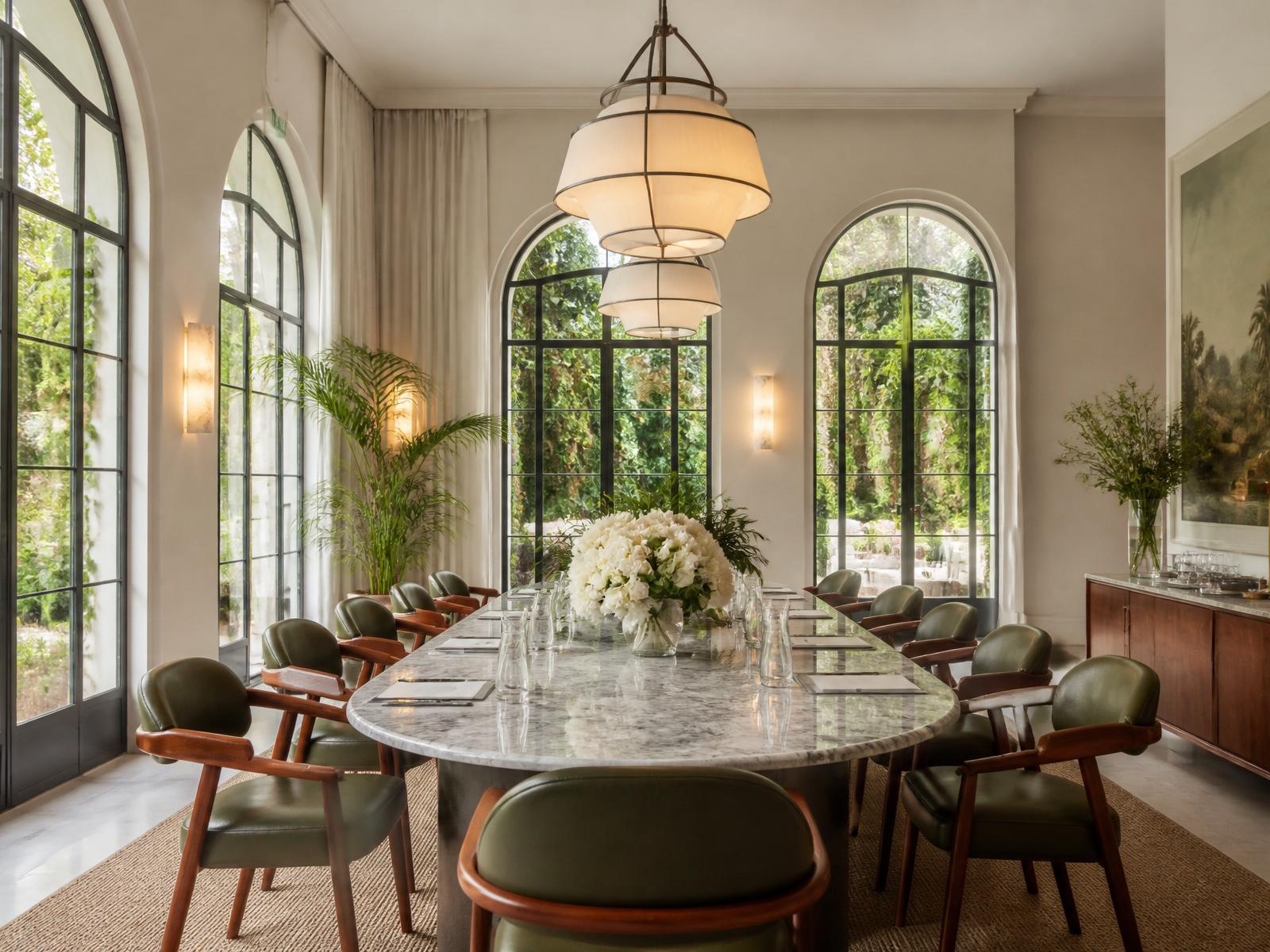 Salón con grandes ventanales, plantas y flores frescas en un hotel boutique